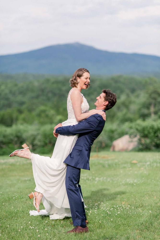 Groom Lifting up Bride Laughing in Front of Mountain View