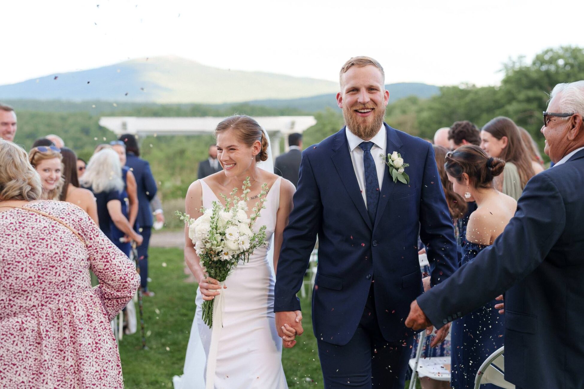 Bride and Groom laughing walking down the aisle at monadnock berries venue with mountain